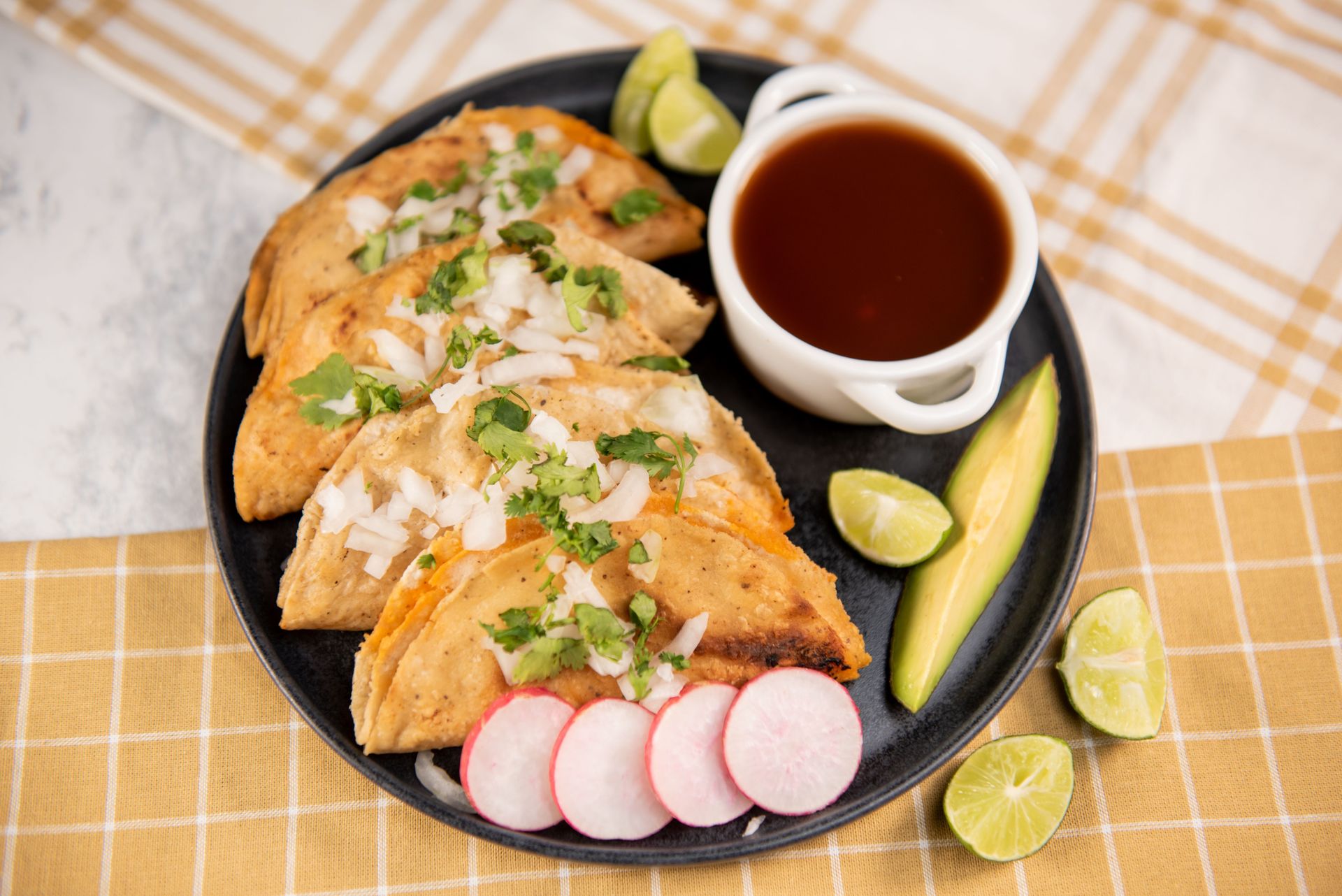 Plate of authentic Mexican street tacos garnished with cilantro, onions, and served with lime wedges and salsa.